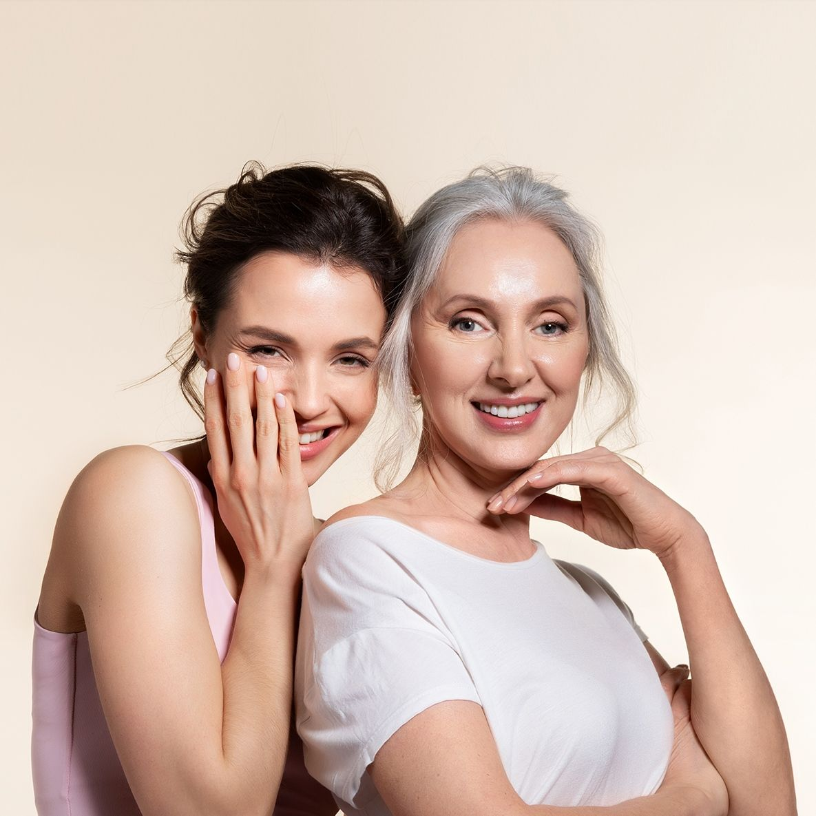 Two women smiling, one with her hand on her cheek